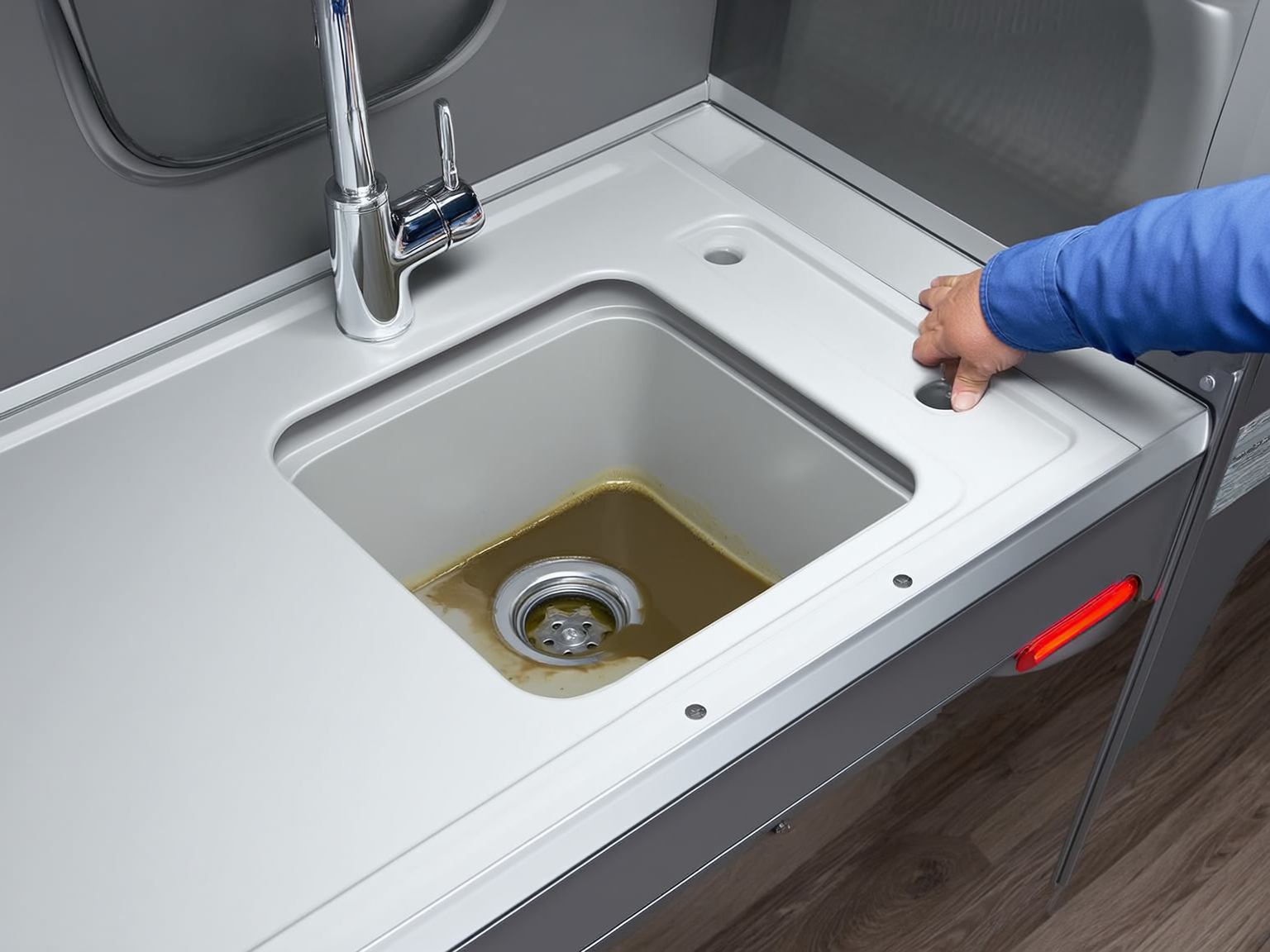 RV kitchen sink and drain area being checked for gray tank odor issues