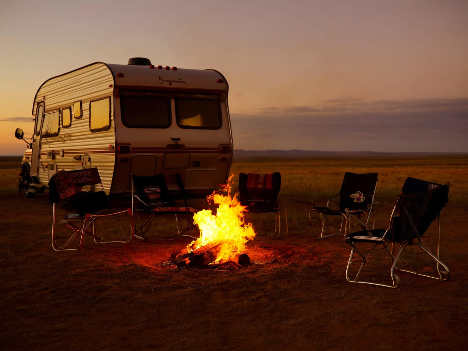 Small controlled campfire beside an RV on a breezy Wyoming summer evening