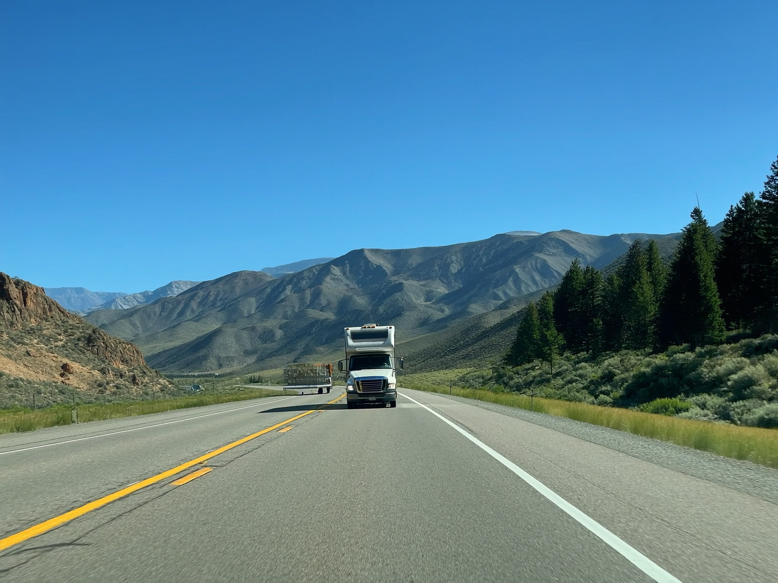 Motorhome driving down a Wyoming mountain grade with dramatic summer landscape