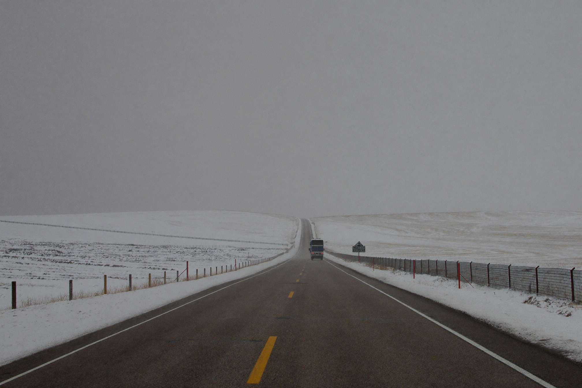 Wyoming highway with snow fences and blowing snow across open plains